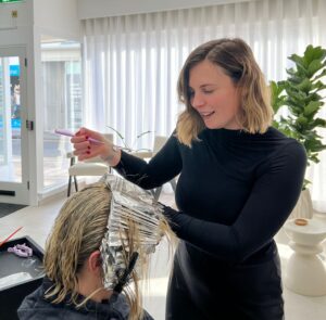 Bleue colouring a client's hair using foils in the salon.